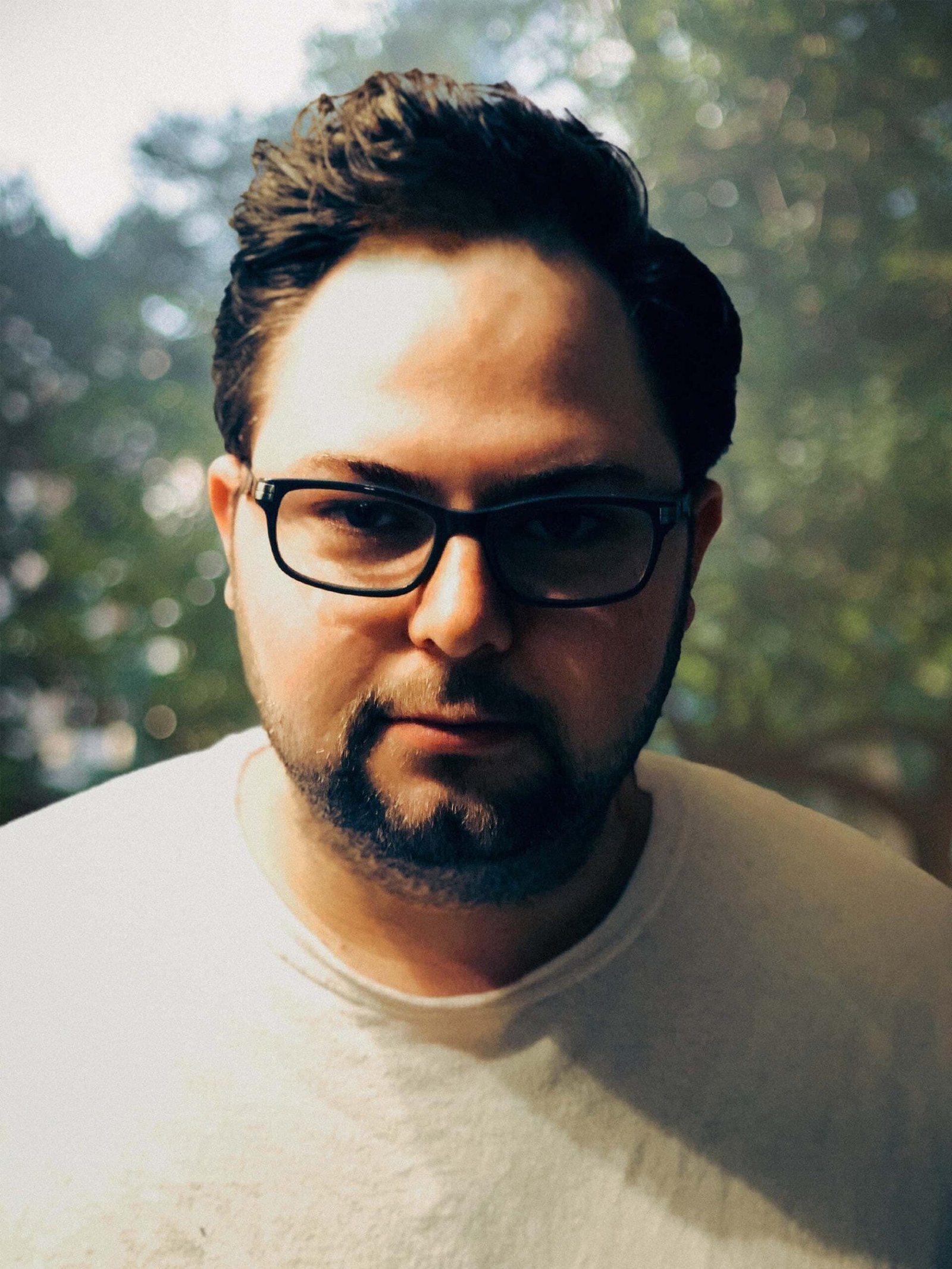 A man wearing glasses and a white t-shirt specializing in Web Design and SEO in New York City.