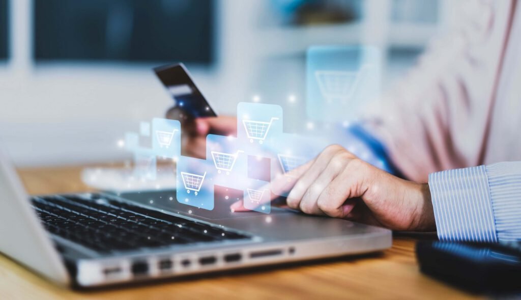 A person uses a laptop and holds a credit card, with digital shopping cart icons overlaid, representing online commerce and e-commerce.