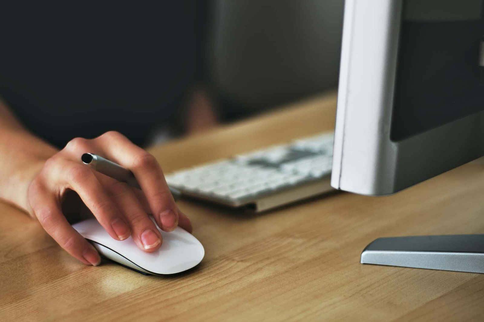 A person using a computer mouse at a desk beside a keyboard and monitor, browsing a Health and Wellness Website.