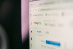 A computer screen displays the Google Analytics dashboard, with the "Analytics" title and navigation menu visible on the left side, tracking SEO performance for businesses in Queens and Manhattan.