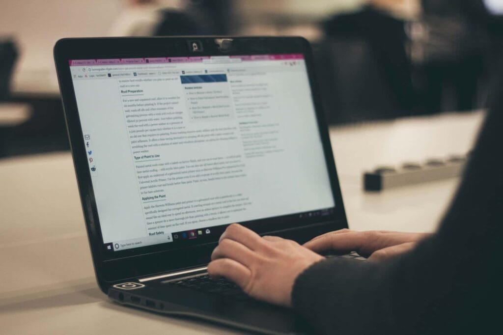 A person is typing on a laptop with an SEO document open on the screen in a workplace or study environment.