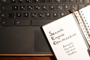 A notebook labeled "SEO Search Engine Optimization" with related keywords rests on a laptop keyboard with both English and Greek letters. 10 Essential Tips for Building a WordPress Site with SEO in Mind
