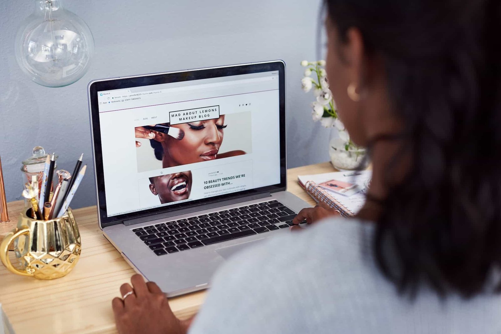 A person sits at a desk using a laptop, viewing a beauty blog website with images of makeup application. Level Up Your Site's User Experience with These 5 Navigation Tips