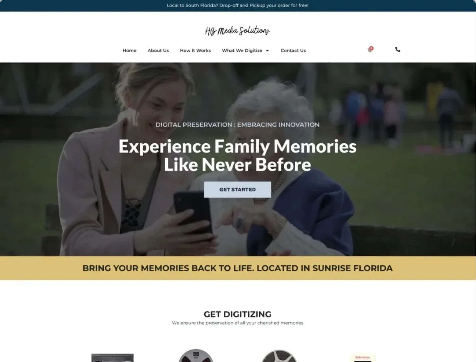 Two women sit on a bench looking at a smartphone together. The website promotes a family memory digitization service based in Sunrise, Florida.