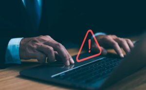 Person in business attire using a laptop with a red warning exclamation mark symbol over the keyboard, indicating a computer or security alert. Top Common Mistakes to Avoid When Building a WordPress Website.