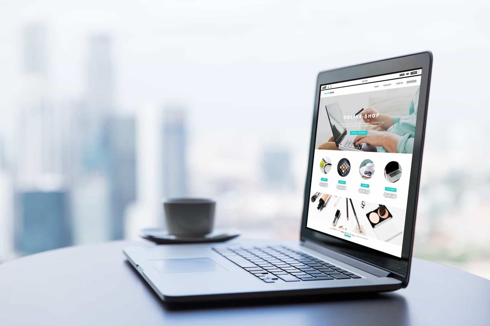 A laptop on a round table displays an online shop website; a cup and saucer sit nearby, with a blurred cityscape in the background.