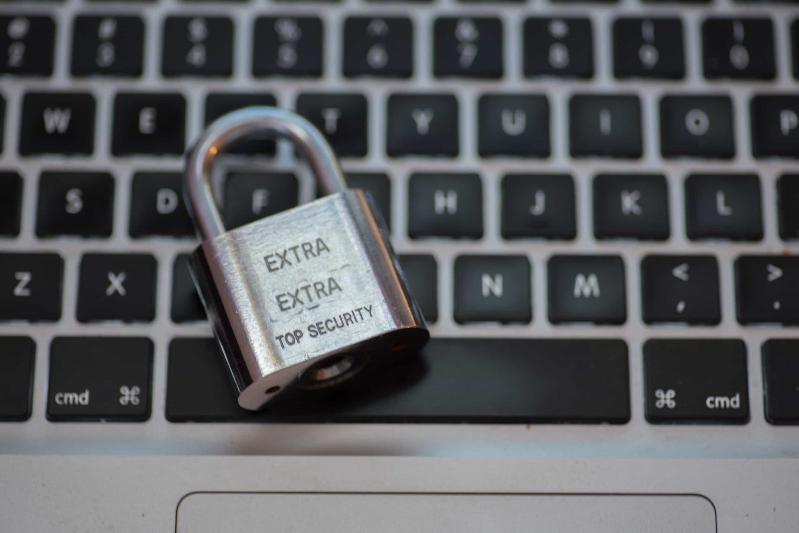 A metal padlock labeled "EXTRA EXTRA TOP SECURITY" rests on a laptop keyboard.