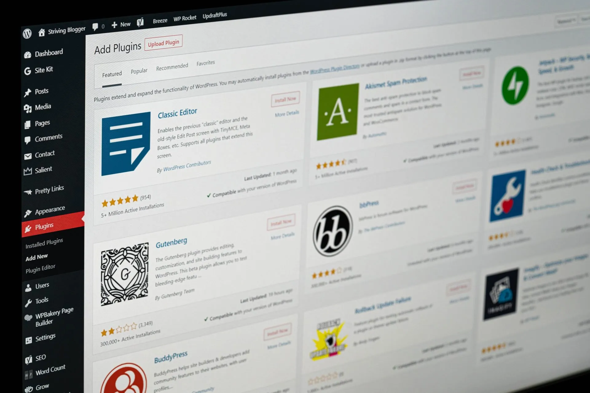 A computer screen displays the WordPress admin dashboard with the "Add Plugins" page open, showing various plugin options and their details. WordPress Security in 2026
