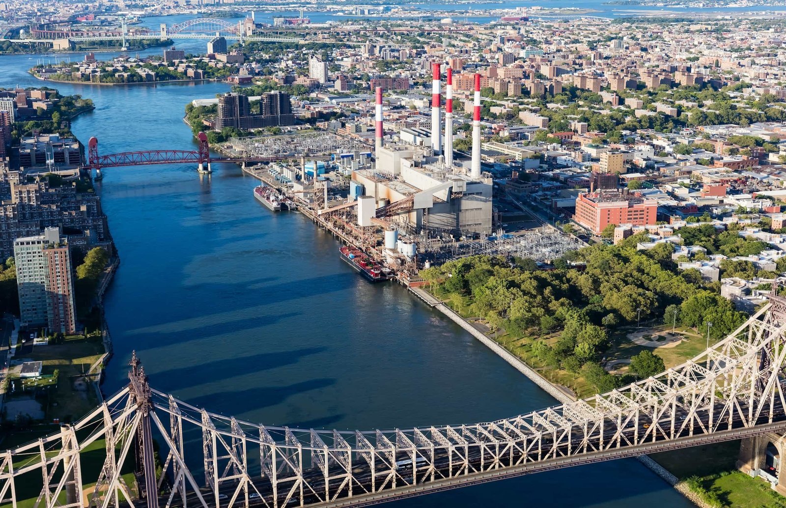 Aerial view of a power plant with tall smokestacks beside a river, surrounded by urban buildings and bridges in a city landscape—perfect for showcasing local SEO efforts within industrial city environments.