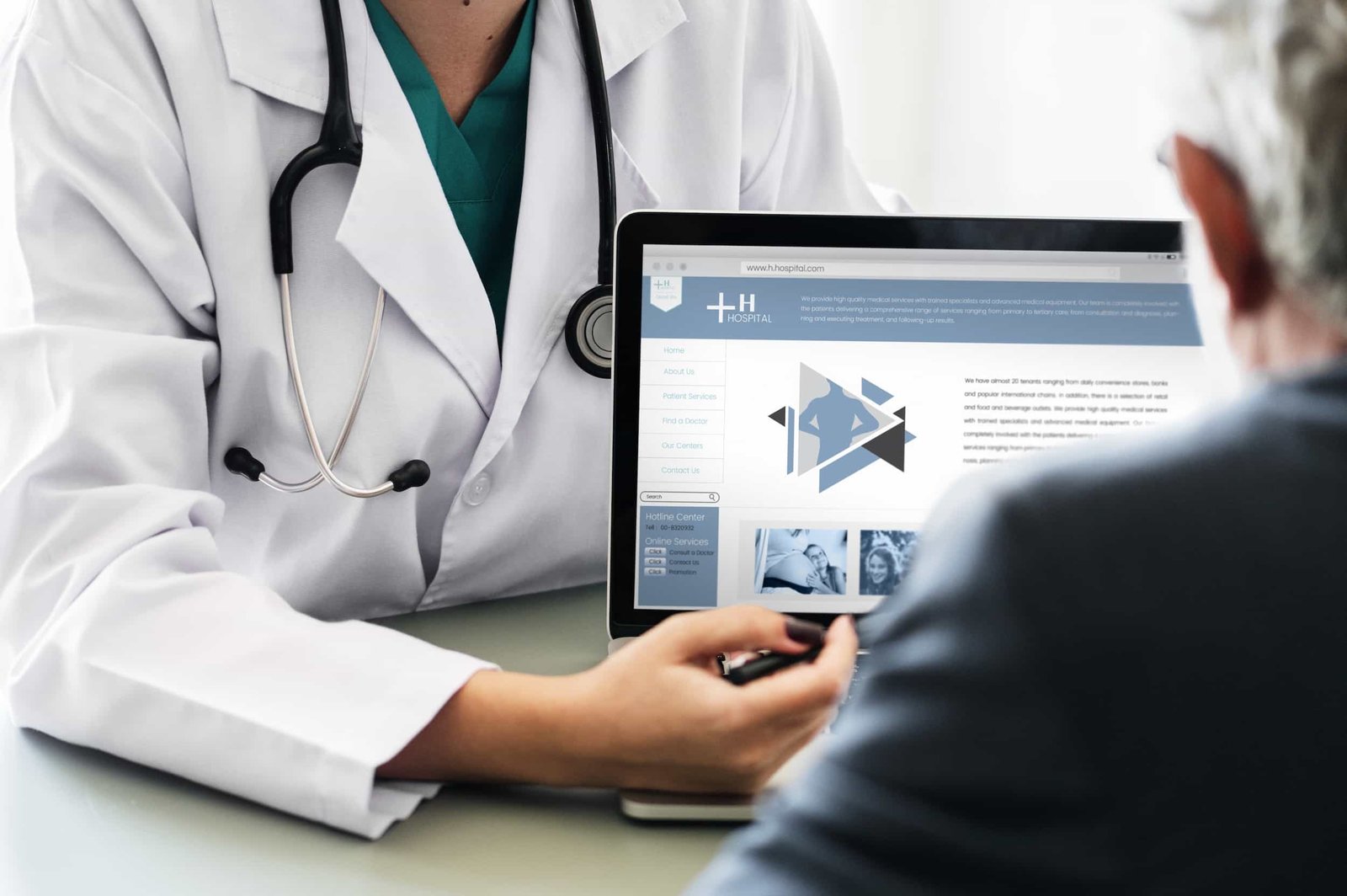 A doctor shows a patient information on a laptop screen during a consultation. Both are seated at a desk, with the laptop displaying a medical website expertly crafted by an NYC Medical Web Designer specializing in SEO.