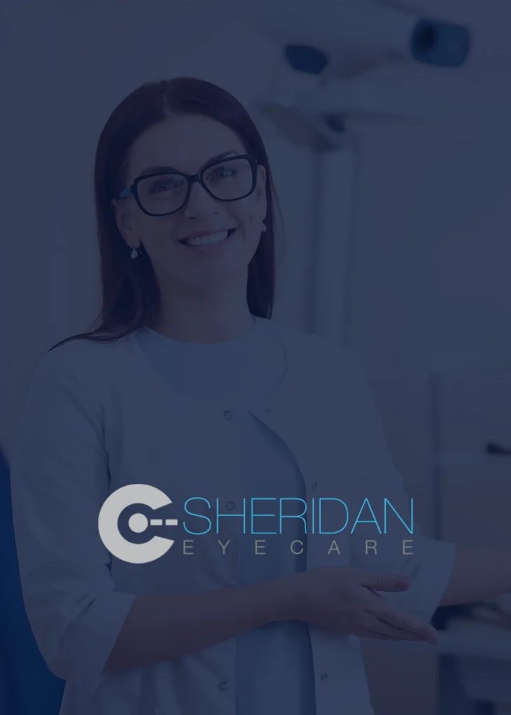 A woman wearing glasses and a white coat smiles in an optometry office. The logo "Sheridan Eyecare" is displayed prominently in the foreground, showcasing the professionalism and attention to detail of a top Medical Web Designer specializing in SEO for NYC practices.