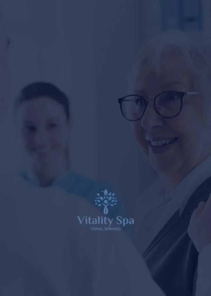 An older woman with glasses smiles while talking to someone, with another person in the background. The Vitality Spa Coral Springs logo is at the bottom of the image, highlighting the brand's professionalism—perfect for a Medical Web Designer seeking inspiration or an SEO specialist in NYC looking to capture genuine moments for healthcare marketing.