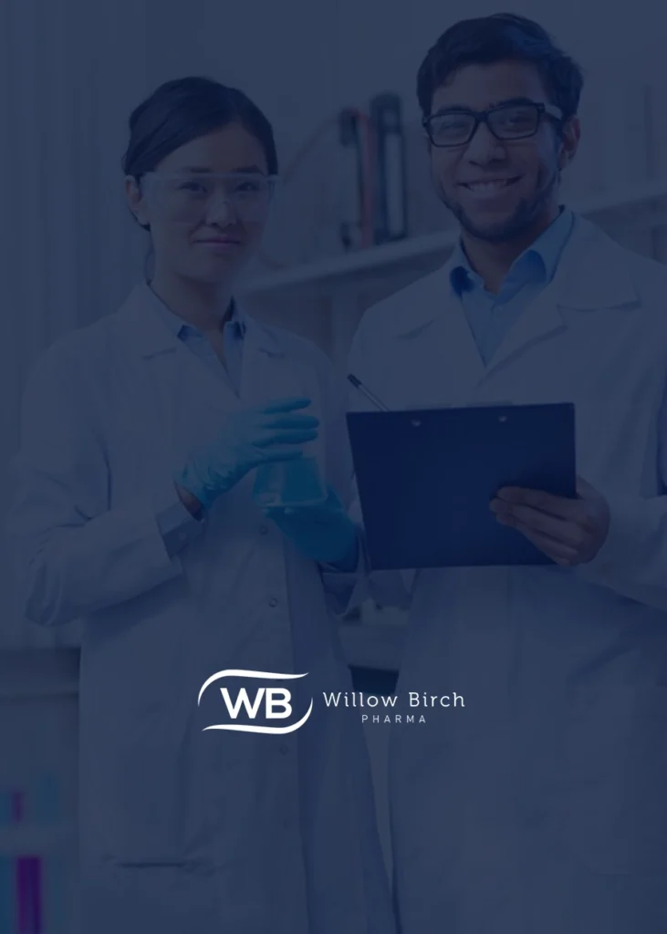 Two scientists in lab coats and safety glasses stand together; one holds a clipboard, the other holds laboratory glassware, illustrating the collaborative spirit at Willow Birch Pharma. The "Willow Birch Pharma" logo is visible at the bottom.