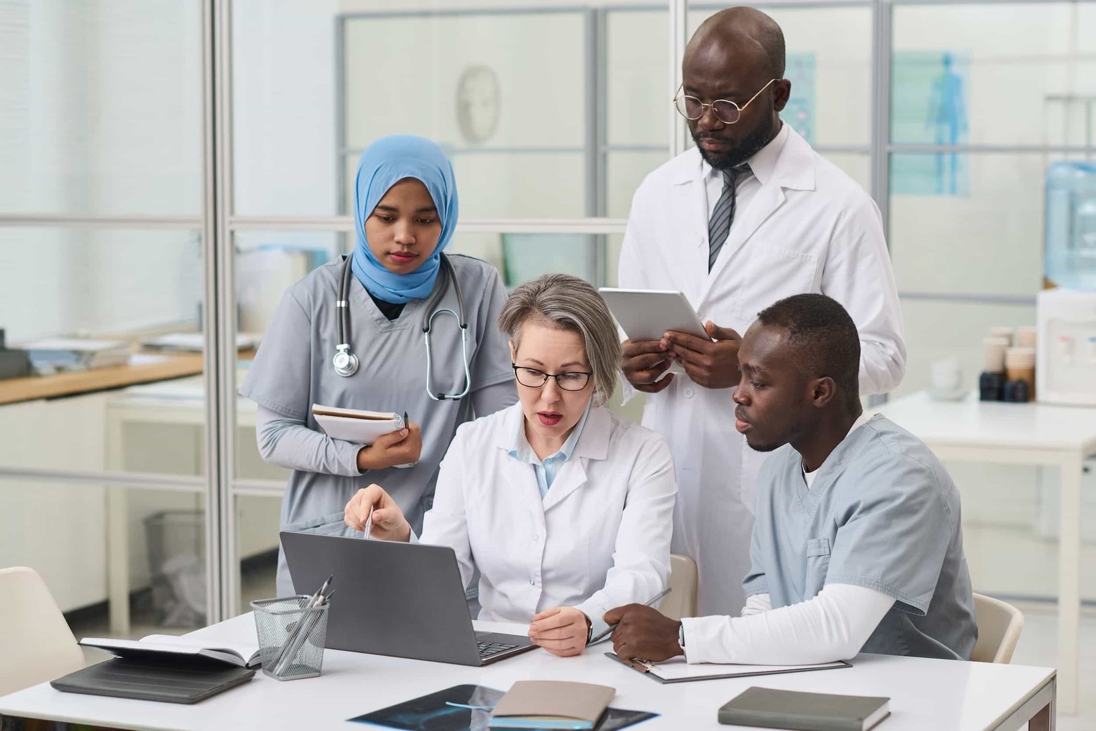Four medical professionals review information together at a table, with laptops and documents in a modern office setting. Why Your EHR Website Isn't Bringing You New Patients