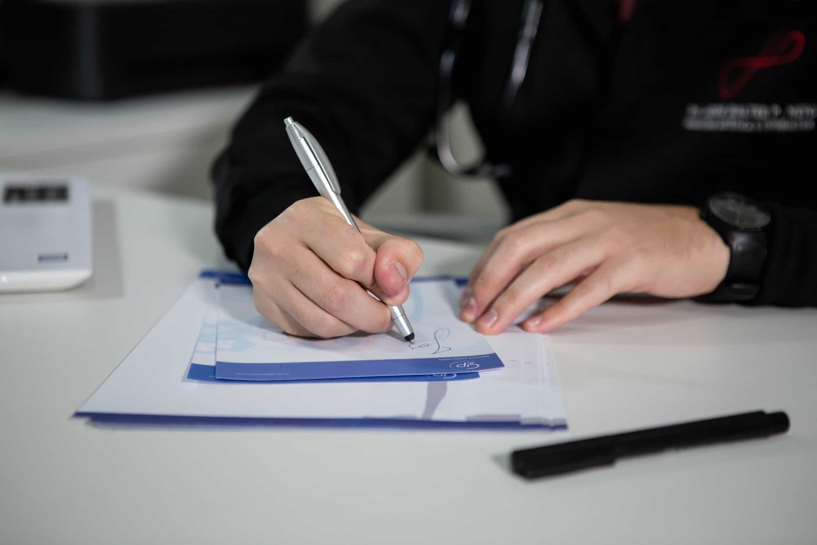 A healthcare professional writing on a notepad with a pen. marketing for a medical practice