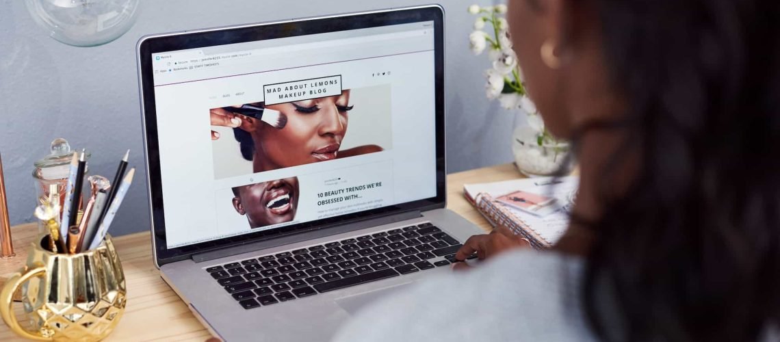 A person sits at a desk using a laptop, viewing a beauty blog website with images of makeup application. Level Up Your Site's User Experience with These 5 Navigation Tips