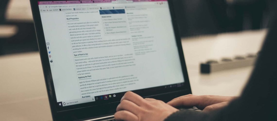 A person is typing on a laptop with an SEO document open on the screen in a workplace or study environment.