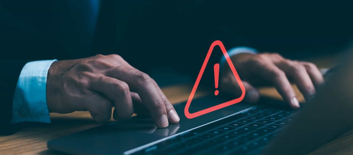 Person in business attire using a laptop with a red warning exclamation mark symbol over the keyboard, indicating a computer or security alert. Top Common Mistakes to Avoid When Building a WordPress Website.