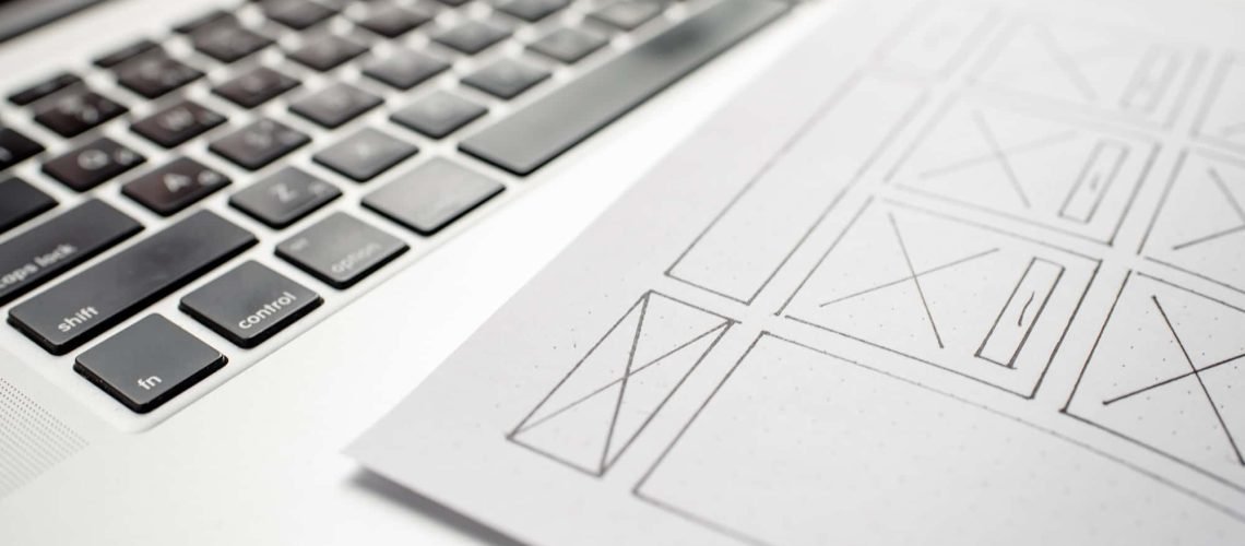 A close-up of a workspace featuring a laptop keyboard and a printed wireframe design for a health and wellness website.